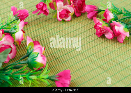 Fleurs en tissu rose sur fond de bambou, gros plan photo. Banque D'Images