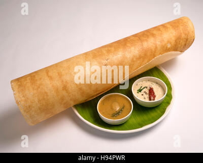 Dosai - dosai rôti roulé croustillant avec sambar et chutney servi sur une feuille de bananier dans une assiette sur fond blanc Banque D'Images