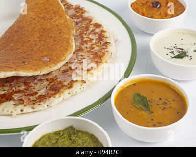 L'uthappam à l'oignon servi dans une assiette avec sambar et trois types de chutneys est une cuisine traditionnelle du sud de l'Inde Banque D'Images