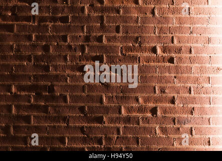 Mur de briques peint rouge avec effet d'éclairage latéral. La texture de fond photo Banque D'Images