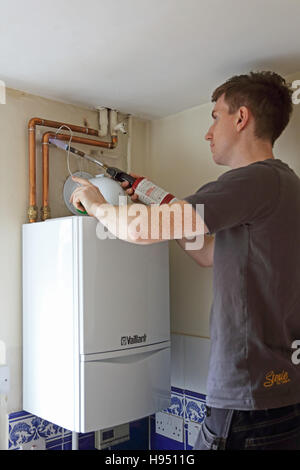 Un jeune plombier utilise un chalumeau pour la conduite d'eau complet de connexions à une chaudière domestique nouvellement installé dans une maison au Royaume-Uni Banque D'Images