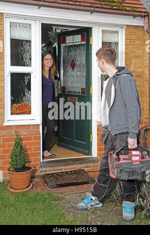 Un jeune plombier/builder et une femme seule parler comme il quitte une maison privée après avoir terminé un travail. Banque D'Images