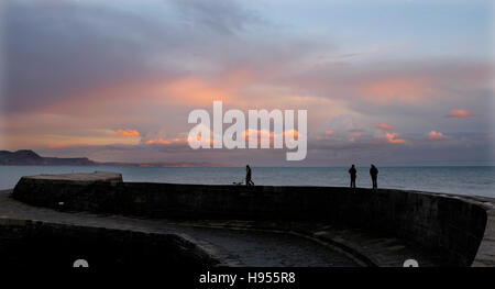 Lyme Regis Dorset, UK. 18 Nov, 2016. Les promeneurs sur la Cobb profiter du magnifique coucher du soleil à Lyme Regis dans le Dorset ce soir Crédit : Simon Dack/Alamy Live News Banque D'Images