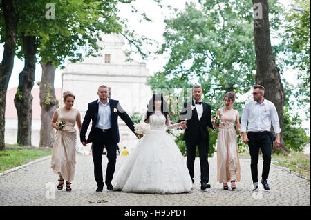 Couple de mariage fine avec demoiselles en robe beige et groomsman marcher au chemin sur parc. Banque D'Images