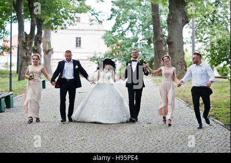 Couple de mariage fine avec demoiselles en robe beige et groomsman marcher au chemin sur parc. Banque D'Images