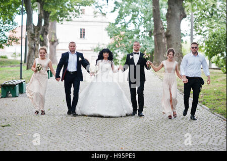 Couple de mariage fine avec demoiselles en robe beige et groomsman marcher au chemin sur parc. Banque D'Images