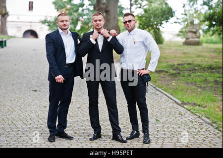 Belle prestance marié avec meilleur mans ou groomsman posés sur parc au jour du mariage. Banque D'Images