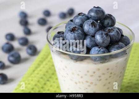 Pouding au tapioca dans un vase en verre clair avec des bleuets frais sur le dessus. Assis sur une table en bois blanc et en tissu vert avec des bleuets frais dans la zone Banque D'Images