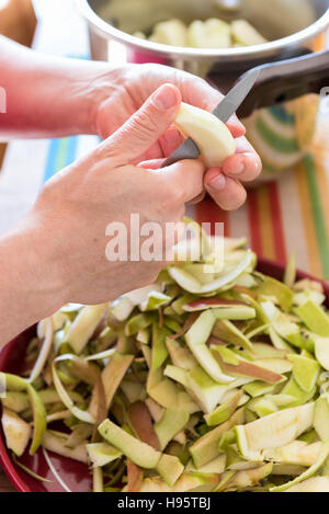 La femme part un peeling apple de cuisson dans une cuisine Banque D'Images