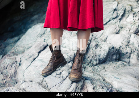 Une jeune femme portant une robe et des bottes de randonnée est debout sur les rochers Banque D'Images