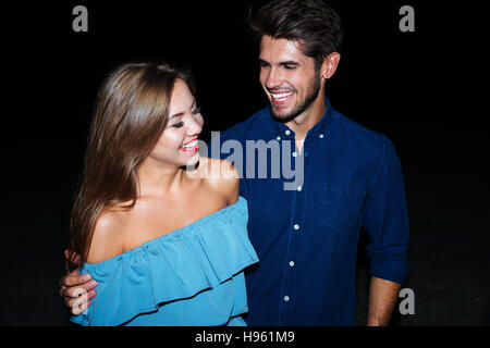 Cheerful young couple hugging and laughing at night Banque D'Images