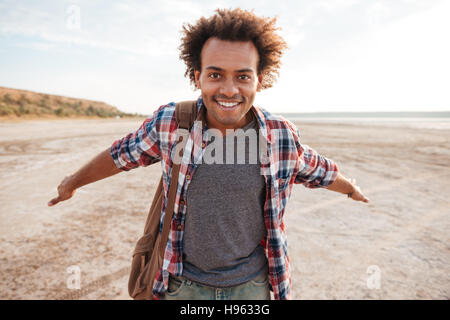 Smiling cute jeune homme africain avec propagation d'armes est ouverte à la plage Banque D'Images