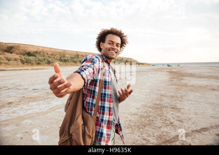 Happy african american man avec sac à dos, vous invitant à aller avec lui Banque D'Images