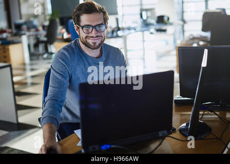 Portrait of smiling businessman working at computer in office Banque D'Images