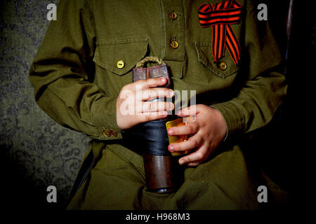 Mains d'un petit garçon sur l'arrière-plan uniforme militaire avec ruban de Saint-Georges Banque D'Images
