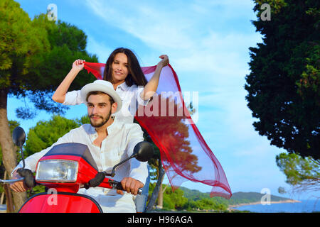 Couple heureux sur un scooter à les vacances d'été Banque D'Images