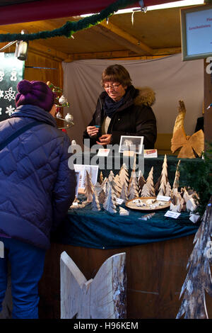 Marché de Noël, le Château de Hohenzollern Hechingen, Allemagne, femme à un stand d'artisanat en bois sculpté discuter chiffres Banque D'Images