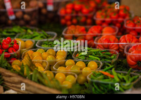 Les tomates cerises et les poivrons chauds dans des paniers en plastique au marché Banque D'Images