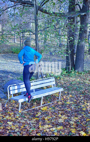 Femme faisant l'étape de l'exercice sur banc de parc Banque D'Images