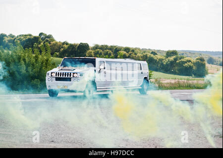 Kiev, Ukraine - 31 août : élégance white wedding limousine Hummer H2 ride couleur de fond de la fumée des cigarettes bombe à jour du mariage. Banque D'Images