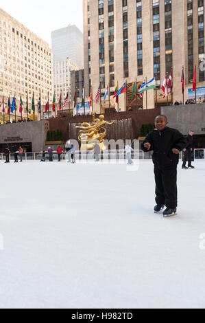 Jeune garçon afro-américain patinant près de la caméra, patinoire du Rockefeller Center, Prometheus Sculpture de Paul Howard Manship, New York Banque D'Images