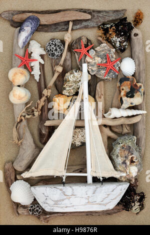 Bateau à voile décoratif sur fond abstrait avec des coquillages, du bois flotté, des rochers et des algues sur le sable. Banque D'Images