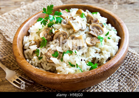 Le risotto aux champignons avec le persil dans un bol en bois close up - Nourriture végétarienne saine Banque D'Images