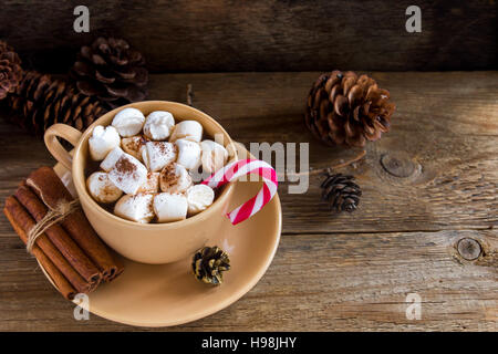 Chocolat chaud avec des guimauves, de la cannelle et de Peppermint Candy Cane sur table rustique close up - boisson festive chaudes faites maison pour Noël et l'hiver h Banque D'Images