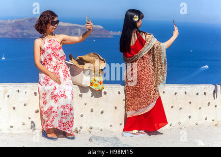 Les touristes asiatiques prenant un selfie avec appareil photo de smartphone au-dessus de caldera, Santorin, île grecque, Grèce touristes Banque D'Images