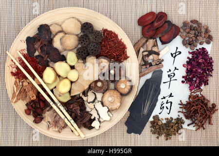 Sélection de la médecine de fines herbes chinoise avec des baguettes sur un bol en bois, aiguilles d'acupuncture et de calligraphie manuscrit sur papier de riz. Banque D'Images