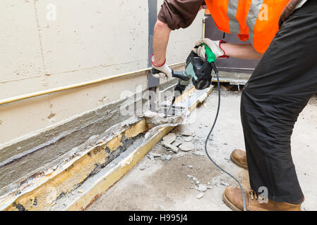 Accueil réparation. Maçon, avec marteau perforateur pneumatique professionnel perforatrice, est la démolition d'une terrasse Banque D'Images