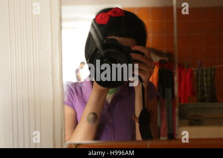 Girl taking a photo dans un miroir avec un appareil photo Banque D'Images