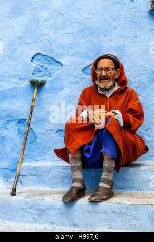 Un vieil homme assis sur un pas dans la rue, Chefchaouen, Maroc Banque D'Images