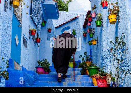 Un homme âgé à monter une rue colorée dans la médina, Chefchaouen, Maroc Banque D'Images