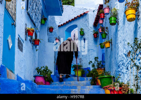 Un homme âgé à monter une rue colorée dans la médina, Chefchaouen, Maroc Banque D'Images
