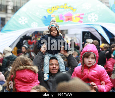 NOTE: PERMISSION PARENTALE ACCORDÉE LJ Lewis, 19 mois (au centre) est assis sur les épaules de son père Lional Lewis, au village de CBeebies au deuxième défilé annuel de jouets de Noël Hamleys sur Regent Street, au centre de Londres. Banque D'Images