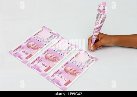 La main de l'enfant tenir 2000 rupee remarque juste comme un stylo. Nouvelle devise indienne de 2000 rupee notes. Banque D'Images