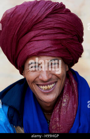 Portrait de nomade bédouine avec turban écarlate et un grand sourire de vendre ses marchandises en destination touristique populaire Ait Benhaddou, Maroc. Banque D'Images