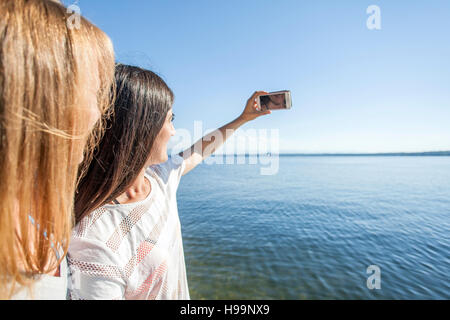 Deux jeunes femmes prenant en selfies lake Banque D'Images