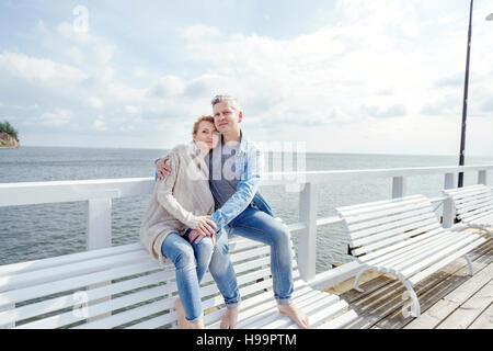 Couple in love sitting on jetty Banque D'Images