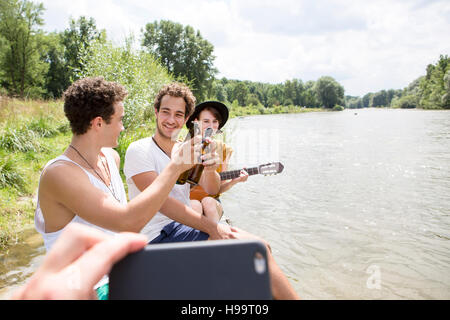 Groupe d'amis se détendre sur la rive Banque D'Images