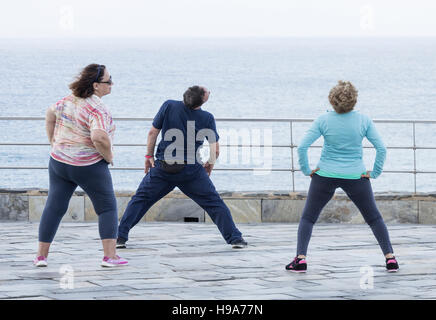 Homme mature et deux femmes mûres pratiquer le Tai chi avec vue sur la mer Banque D'Images