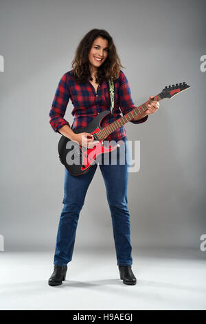 Young Girl playing electric guitar, studio shot on grey Banque D'Images