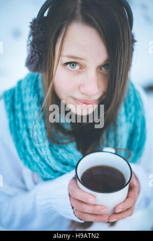 Belle femme de boire une boisson chaude en hiver Parc. Close-up portrait. Focus sélectif. Banque D'Images