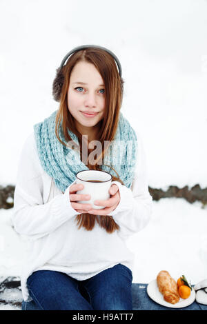 Jeune femme séduisante de boire du thé en plein air en milieu rural de la forêt d'hiver Banque D'Images