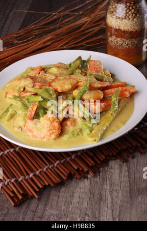 Crevettes épicées de Malaisie dans la sauce au lait de coco sur le haut fond de bois Banque D'Images