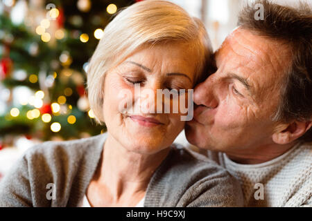 Senior couple in front of Christmas Tree kissing, Close up. Banque D'Images