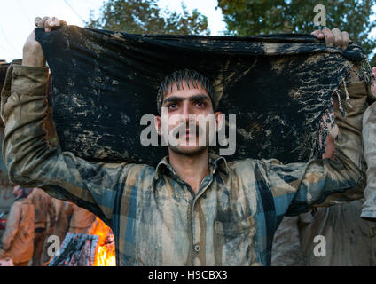 L'homme musulman chiite iranien séchant ses vêtements après le frottement de la boue sur son corps pendant l'kharrah rituel du Mali à l'occasion de la cérémonie d'Ashura, Lorestan bauvin Banque D'Images