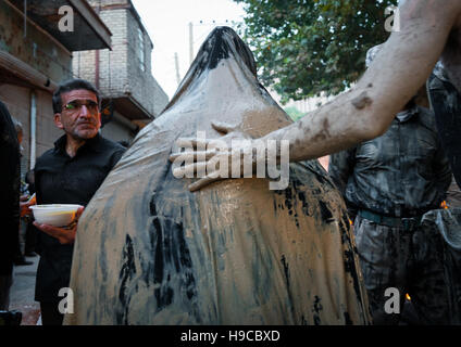 L'homme musulman chiite iranien à la tête d'une femme couverte de boue pendant le rituel kharrah mali pour marquer le jour de ashoura, la province du Lorestan, Khorramabad, Iran Banque D'Images