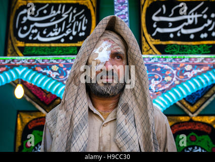 L'homme musulman chiite iranien avec un oeil blessé après le frottement de la boue sur ses vêtements pendant le rituel kharrah le Mali à l'occasion de la cérémonie d'Ashura, Lorestan pro Banque D'Images